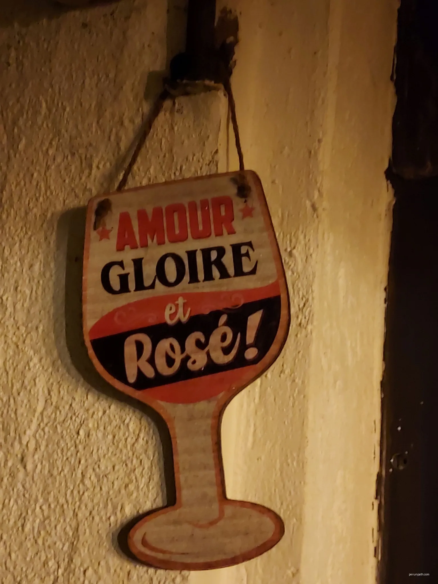 Publicité pour le vin avec le slogan "Amour, gloire et rosé" dans le bar-restaurant "Chez Seb" à Trèbes. | Autor: Fabricio Cardenas | Licencja: CC BY-SA 4.0 | Źródło: Wikimedia Commons