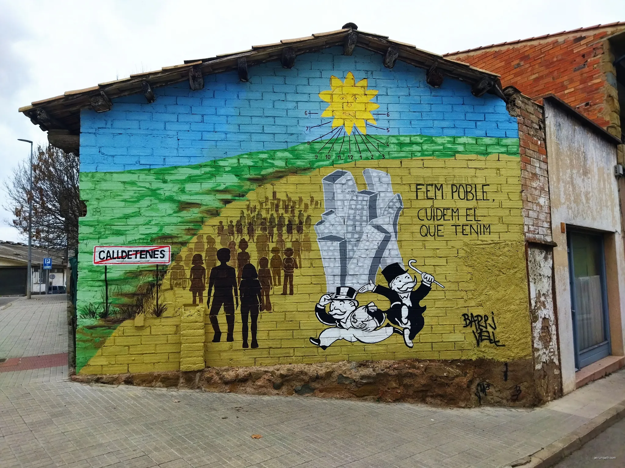 Mural al Barri Vell de Calldetenes, amb el text: "Fem poble, cuidem el que tenim" | Autor: Manuel C. | Licencja: CC BY-SA 4.0 | Źródło: Wikimedia Commons