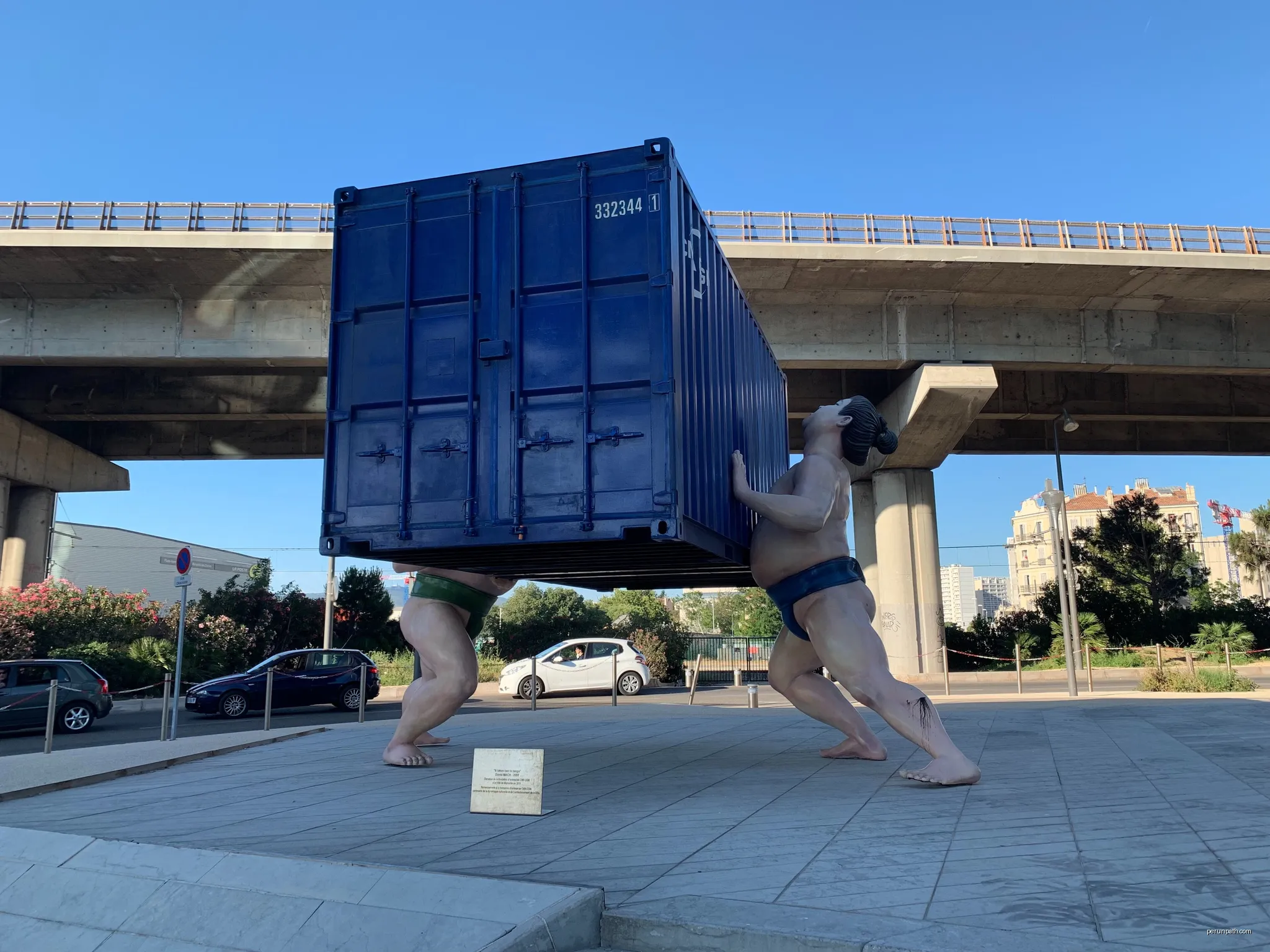 Sculpture of sumo fighters lifting a container | Autor: Rberchie | Licencja: CC BY-SA 4.0 | Źródło: Wikimedia Commons