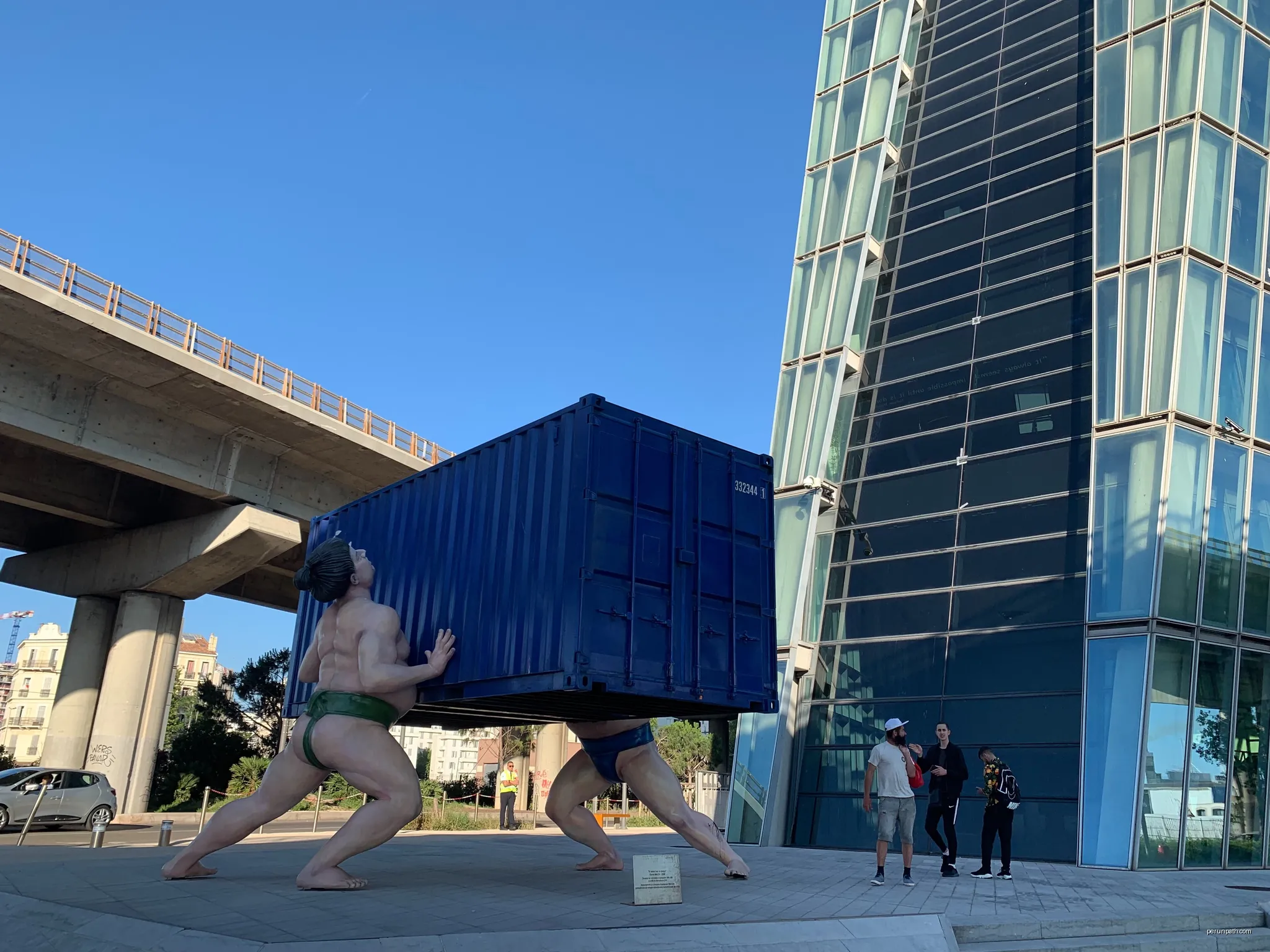 Sculpture of sumo fighters lifting a container | Autor: Rberchie | Licencja: CC BY-SA 4.0 | Źródło: Wikimedia Commons