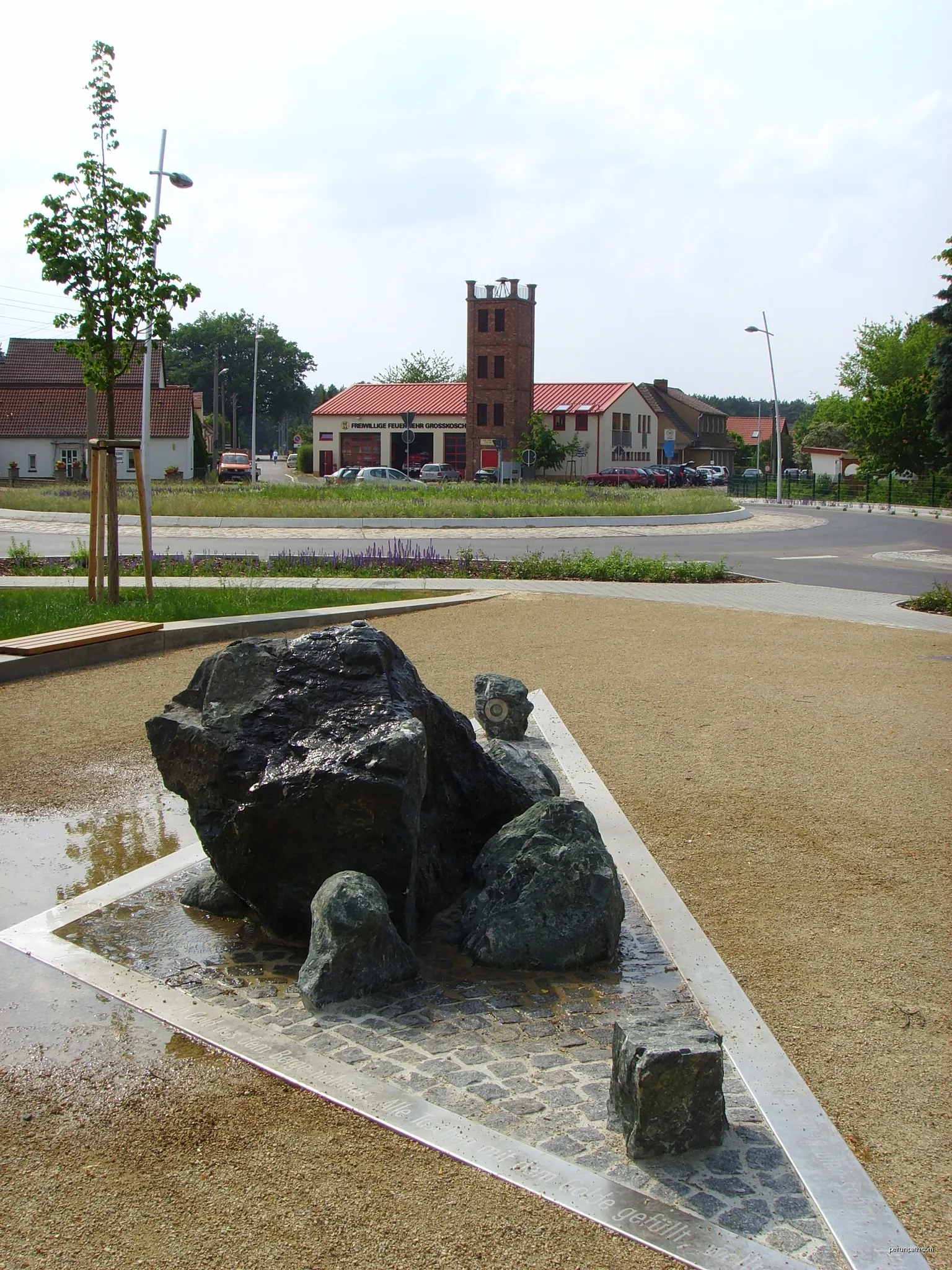 Brunnen im Senftenberger Ortsteil Großkoschen, im Hintergrund die Feuerwache | Autor: Z thomas | Licencja: CC BY 3.0 | Źródło: Wikimedia Commons
