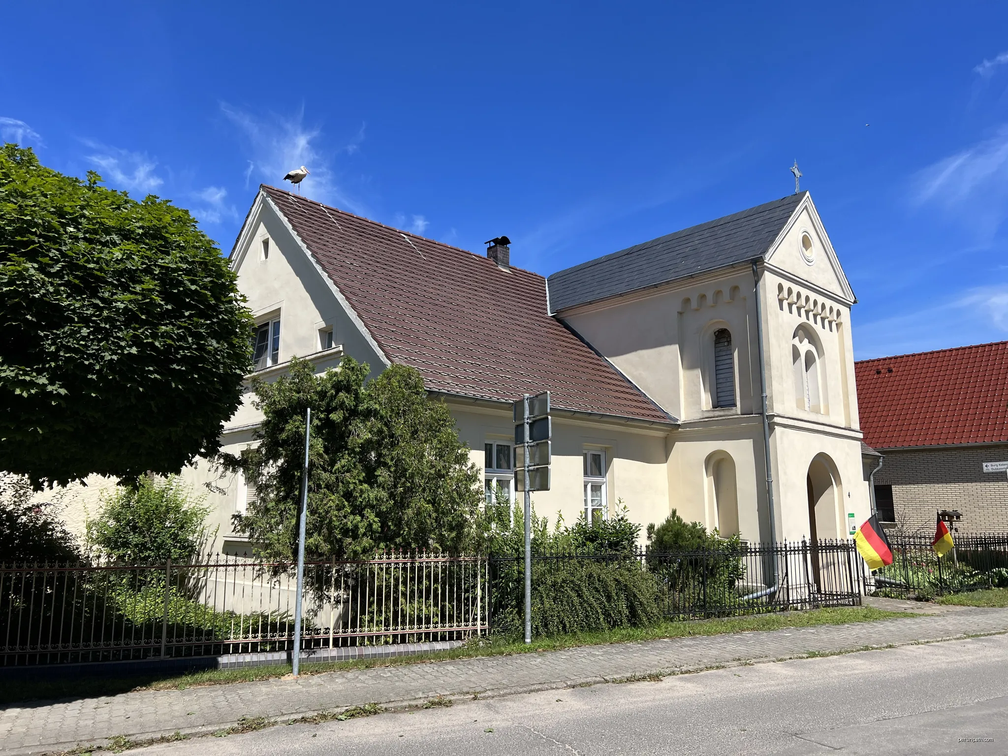 Ehemalige Schule, heute Wohnhaus in Raddusch, Landkreis Oberspreewald-Lausitz, Brandenburg, Deutschland. Auf dem Dach sitzt ein Storch. | Autor: Lukas Beck | Licencja: CC BY 4.0 | Źródło: Wikimedia Commons