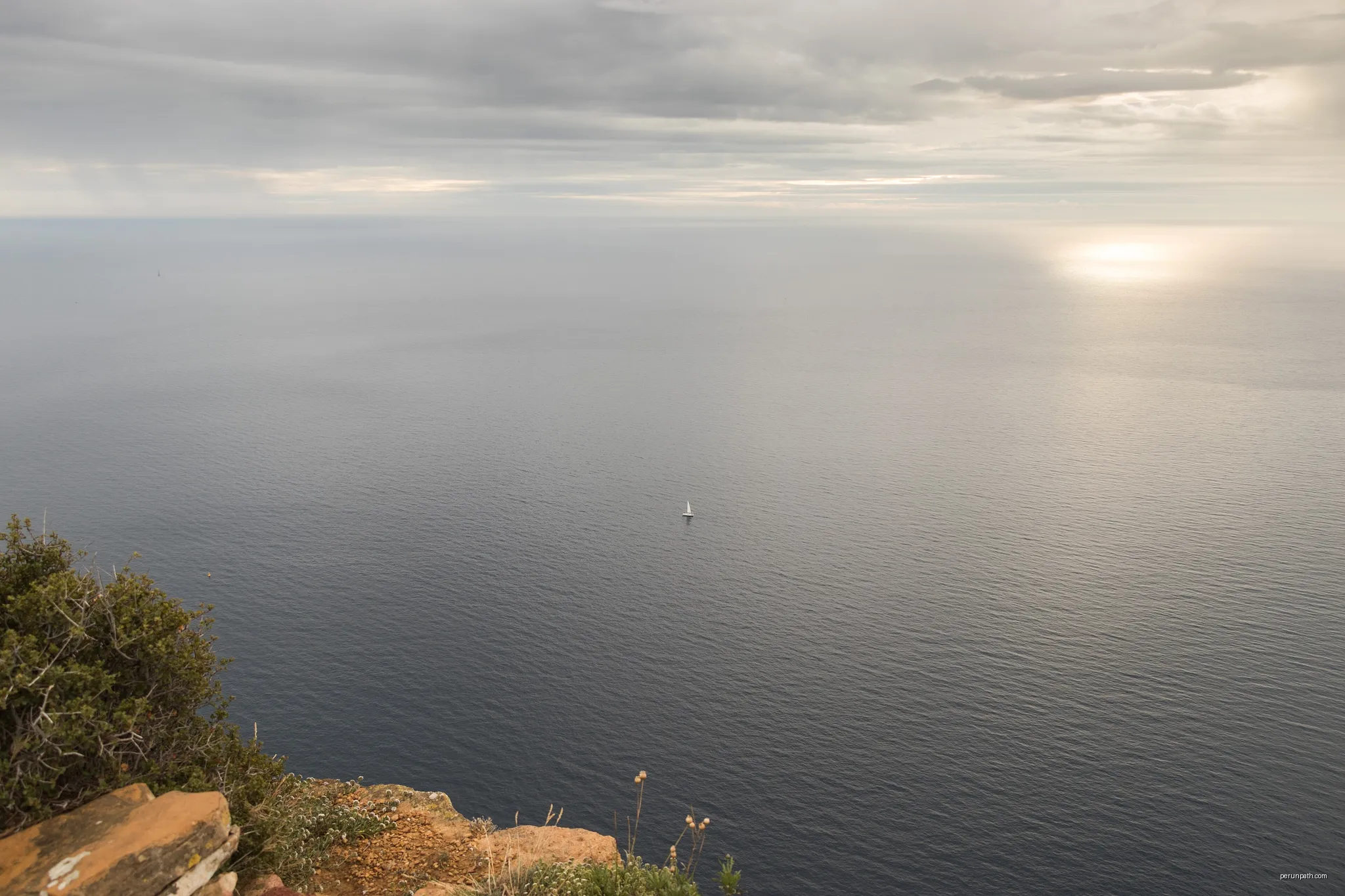 Vue sur la mer depuis la route des crêtes, avec un petit voilier, un ciel chargé et un reflet de soleil sur l'horizon | Autor: Pierre Goiffon | Licencja: CC BY-SA 4.0 | Źródło: Wikimedia Commons