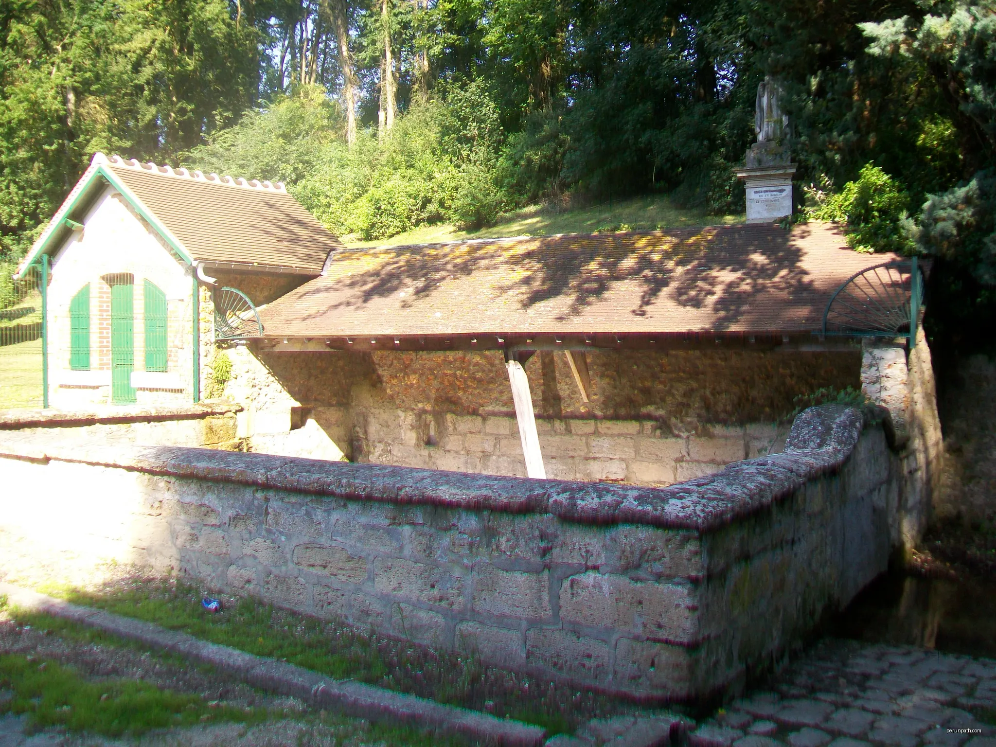 La fontaine Saint-Romain, aménagée en lavoir, accompagnée d'un abreuvoir et surplombée par une statue de Saint-Romain. Près de la RD 159 entre Guiry et Wy. | Autor: P.poschadel | Licencja: CC BY-SA 3.0 | Źródło: Wikimedia Commons
